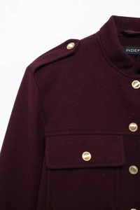 Detail of burgundy wool jacket with gold metal buttons and premium textured fabric finish