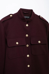 Detail of burgundy wool jacket featuring gold metal buttons and functional flap pockets