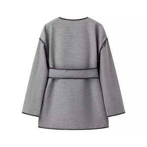 Back view of minimalist grey wool coat with black contrast piping and waist belt detail