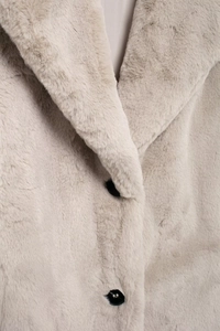 Detail of faux fur coat collar and black buttons on light beige plush winter outerwear