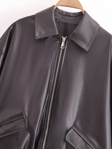 Detail der schwarzen Kunstlederjacke mit klassischem Kragen und silbernem Reißverschluss