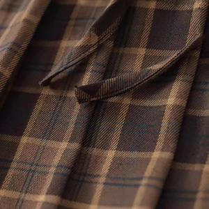 Close-up of brown plaid mini skirt with pleated texture and matching waist tie detail