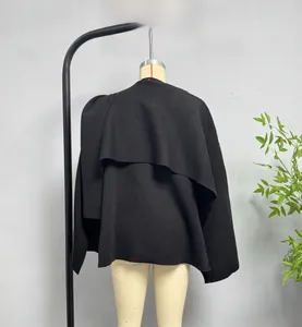 Detail view showing thick knitted texture and asymmetric layered back of a black cape