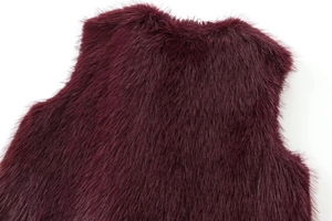 Détail de la texture d'un gilet en fausse fourrure bordeaux avec fibres synthétiques