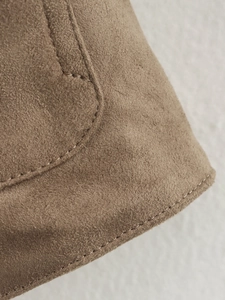 Detailaufnahme von braunem Wildleder mit feinen Nähten und weicher, matter Textur