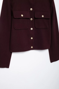 Close-up of wool jacket featuring golden metal buttons and symmetrical flap pockets