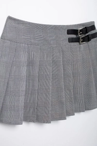 Détail de la jupe plissée à carreaux gris avec boucles en cuir noir et texture du tissu