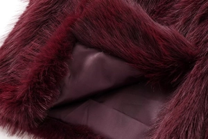 Détail de gilet en fausse fourrure bordeaux avec texture douce et doublure soyeuse