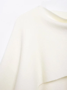 Detail view of the asymmetrical cream knit shawl highlighting fine wool-like fabric texture
