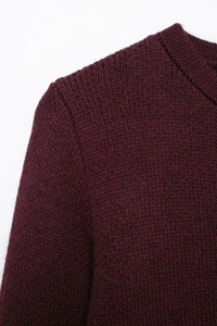 Close-up of dark burgundy knit sweater showing round neck detail and stitch texture