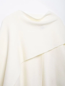 Detail of soft white knit shawl collar showing elegant draped neckline and fine texture