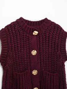 Close-up of chunky knit burgundy vest featuring irregular golden wave metal buttons