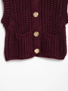 Detail of chunky knit texture in burgundy with irregular gold metallic buttons