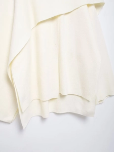 Detail of soft cream white knit texture and drape on stylish women's poncho sweater