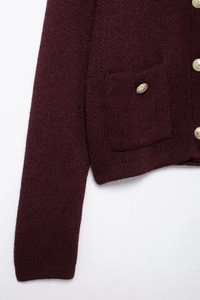 Close-up of wine red knit cardigan featuring texture and vintage gold embossed buttons