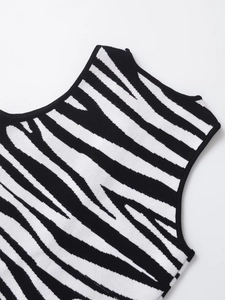 Detail of knit vest showing zebra pattern and black piping on the neckline and armhole