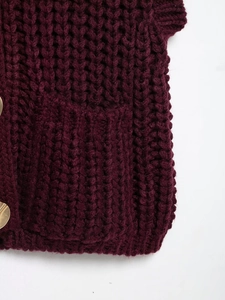 Detail of chunky knit vest with wine red texture and golden metallic side buttons