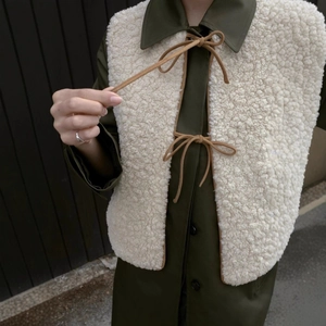 Chic cream fleece vest with brown lace-up details and trim over olive wool coat