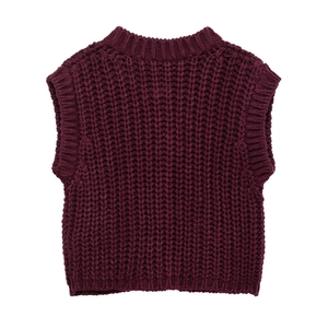 Close-up of chunky knit texture and ribbed hem on a burgundy sleeveless sweater vest
