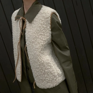 Women's cream fleece vest with brown ties and plush faux shearling texture over olive jacket