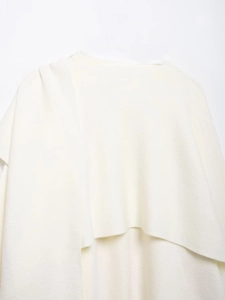Close-up of cream knit fabric texture on an asymmetric short-sleeved cardigan