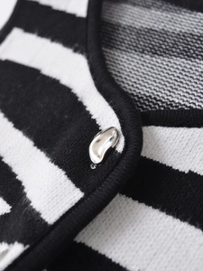 Detailed close-up of black and white striped knit fabric with a silver metallic button