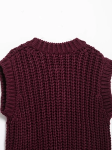 Detail of chunky knit vest featuring ribbed neckline and openwork weave pattern