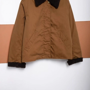 Detailed view of brown canvas jacket featuring black fleece collar and large side pockets