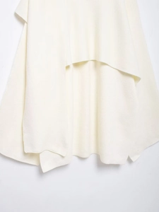 Detailed view of the layered knit fabric texture and asymmetrical hem of the white poncho