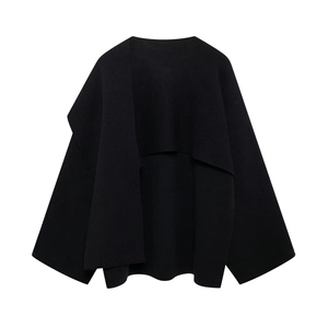 Detail of black asymmetrical knit top featuring a draped shawl-style wrap and batwing sleeves