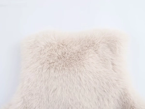 Close-up of beige faux fur material with soft, long plush texture and glossy finish