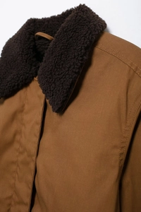 Detail of winter canvas jacket featuring deep brown sherpa fleece collar and double-stitched seams