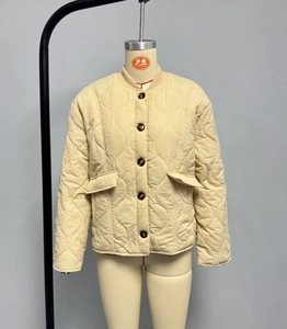 Close-up detail of beige quilted jacket with wavy stitching and front button closure