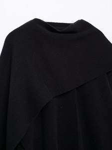 Close-up of the overlapping knit collar and soft texture on this black poncho sweater