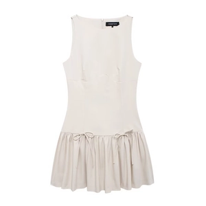 Détails d'une élégante robe courte sans manches crème avec nœuds et ourlet plissé