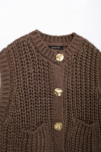 Close-up of brown chunky knit vest featuring decorative irregular gold metal buttons