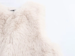 Detailed macro view of soft cream faux fur texture and fluffy pile on a winter vest