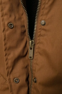 Macro detail of bronze metal zipper and vintage buttons on brown workwear canvas jacket