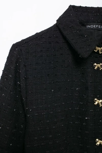 Détail du tweed noir aux fils métalliques et boutons dorés en forme de nœud élégant