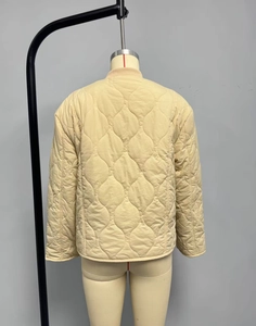 Back view of beige quilted jacket featuring classic onion stitching and ribbed collar