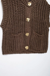 Close-up of brown knit vest with chunky texture and irregular gold metal buttons