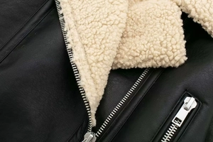 Detail of black leather texture and white faux shearling lining with silver metal zipper