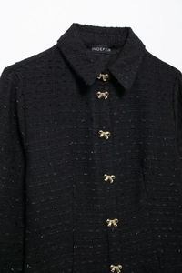 Détail d'une mini robe en tweed à manches longues avec des boutons nœuds dorés sur blanc