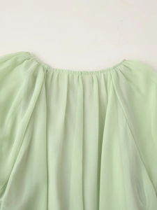 Detail of the elastic gathered neckline on light green chiffon blouse with sheer fabric texture