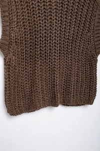 Close-up of brown chunky knit vest showing honeycomb texture and ribbed hem detail