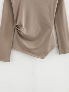 Detail view showing side ruched draping and asymmetrical hem on long sleeve top