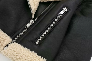 Close-up of black leather texture and thick cream faux fur lining on jacket lapel