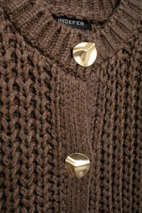 Detailed macro view of dark brown chunky knit vest featuring gold geometric metal buttons