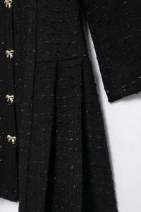 Détail de robe en tweed noir avec fil métallique argenté et boutons noeuds dorés