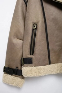 Détail d'une veste en daim kaki avec ourlet en peau de mouton et fermeture éclair bronze